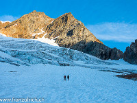 Drei Seilschaften sind heute am Ostgrat unterwegs, wir reihen uns in der Mitte ein. Der Schnee auf dem Brunnenfirn ist hart gefroren, weshalb wir die Steigeisen montieren. Von hier lässt sich der ganze Ostgrat gut überblicken. Der Einstieg zur Gratkkletterei befindet sich bei der tiefsten Einsattelung rechts im Bild. : Aufstieg, Brunnenfirn, Gletscher, Seilschaft, Sonnenaufgang, Sustenhorn Ostgrat